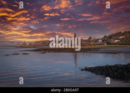 Largs preannunciava di guardare oltre il Pencil Monument alla città stessa, mentre il tramonto lascia colori drammatici nelle skys sopra la città. Foto Stock