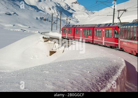 Bernina treno rosso che corre nella neve nelle alpi svizzere in inverno Foto Stock