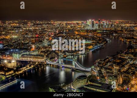 Vista aerea del Tower Bridge e di Londra dopo il tramonto che mostra il molo delle canarie e la città lungo il Tamigi Foto Stock