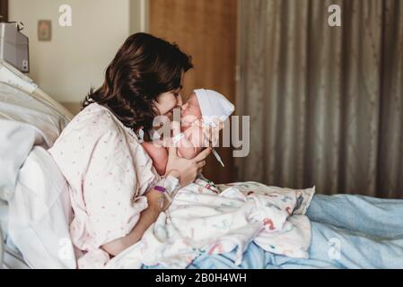 Vista laterale della madre e del neonato che toccano i nasi in ospedale Foto Stock