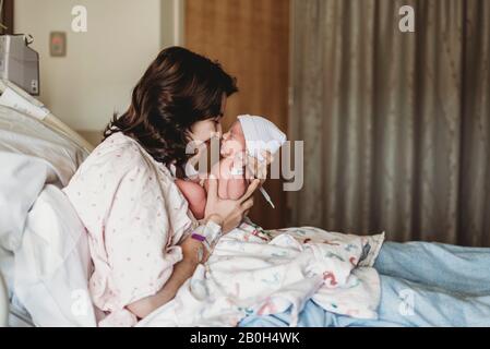 Vista laterale della madre e del neonato che toccano i nasi in ospedale Foto Stock