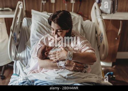 Vista centrale della madre nel letto dell'ospedale che guarda il figlio neonato Foto Stock