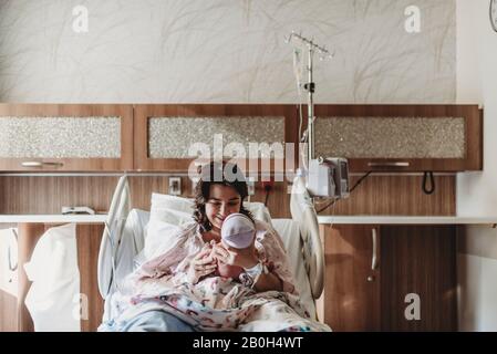 Vista centrale della madre nel letto dell'ospedale che guarda il figlio neonato Foto Stock