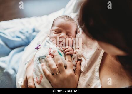Vista dall'alto della madre che tiene le dita del neonato nel letto dell'ospedale Foto Stock