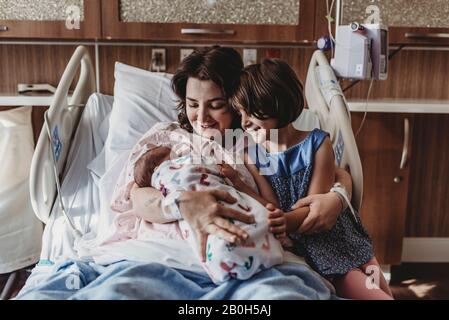 Vista centrale della madre che tiene il figlio neonato che incontra la sorella Foto Stock