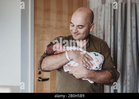 Il padre felice che tiene il bambino neonato avvolto in coperte in ospedale Foto Stock