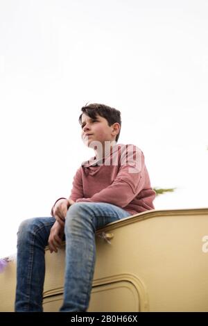 Vista bassa di un ragazzo seduto sulla cima di una carovana Foto Stock