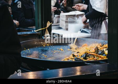 Grande panino di paella in un mercato alimentare di strada, persone non identificabili sullo sfondo, fuoco selettivo. Foto Stock