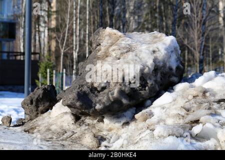 Molta neve velata con un sacco di piccole rocce fotografate durante una soleggiata giornata primaverile a Espoo, Finlandia, febbraio 2019. Alberi sullo sfondo. Foto Stock