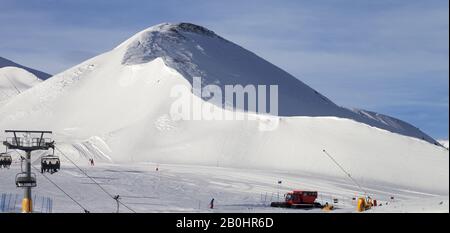 Pista da sci innevata preparata con macchina da neve, seggiovia, cannoni da neve e gatto delle nevi presso la stazione sciistica. Montagne in inverno. Alpi Italiane. Livigno, r Foto Stock