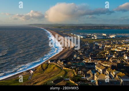 Fortuneswell, Portland, Dorset, Regno Unito. 20th febbraio 2020. Meteo Regno Unito. Vista dalla cima delle scogliere di West Weares attraverso Fortuneswell sull'Isola di Portland a Dorset durante il tardo pomeriggio sole con vento frettoloso e mari accidentati che si infrangono a riva su Chesil Beach a Chiswell. Foto Di Credito: Graham Hunt/Alamy Live News Foto Stock