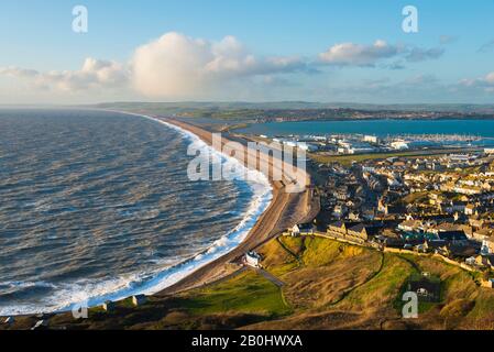 Fortuneswell, Portland, Dorset, Regno Unito. 20th febbraio 2020. Meteo Regno Unito. Vista dalla cima delle scogliere di West Weares attraverso Fortuneswell sull'Isola di Portland a Dorset durante il tardo pomeriggio sole con vento frettoloso e mari accidentati che si infrangono a riva su Chesil Beach a Chiswell. Foto Di Credito: Graham Hunt/Alamy Live News Foto Stock