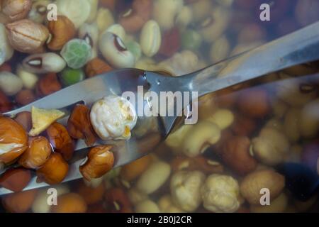 Vista degli impulsi, dei cereali, dei fagioli e dei piselli imbevuti in acqua come fase di preparazione per cucinare. Foto Stock