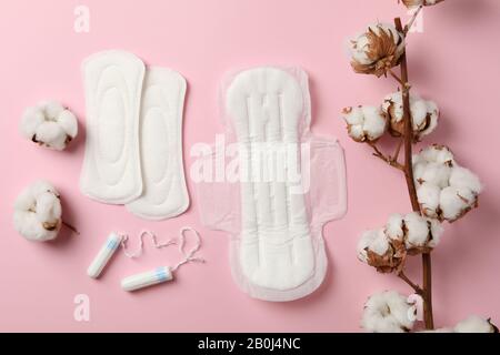 Assorbenti igienici, tamponi e cotone su sfondo rosa Foto Stock