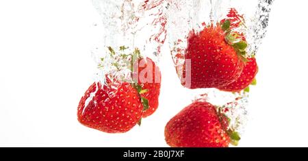 Le fragole di cadere in acqua causando bolle tutto intorno. Cibo sano concetto Foto Stock