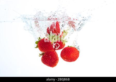 Le fragole di cadere in acqua causando bolle tutto intorno. Cibo sano concetto Foto Stock