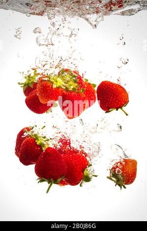 Le fragole di cadere in acqua causando bolle tutto intorno. Cibo sano concetto Foto Stock