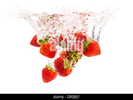 Le fragole di cadere in acqua causando bolle tutto intorno. Cibo sano concetto Foto Stock