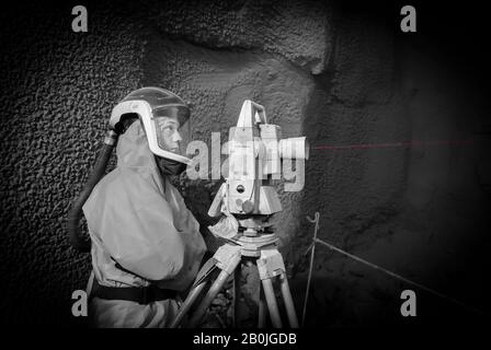 Un operatore di abbigliamento protettivo controlla le apparecchiature per il tunneling con un fascio laser per LUL BSCU (Bank Station Capacity Upgrade) a Londra EC4 Foto Stock