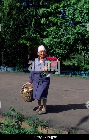 RUSSIA, VICINO A YAROSLAVL, STAZIONE DANILOV, DONNA CON PEONIE Foto Stock