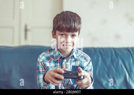 Ragazzino che gioca a videogame da controller a casa Foto Stock