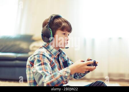 Il giovane giocatore si concentra mentre gioca, tenendo il controller Foto Stock