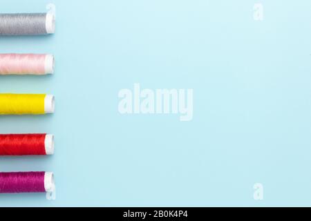 Fili colorati per cucire su uno sfondo blu. Foto Stock