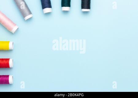 Fili colorati per cucire su uno sfondo blu. Foto Stock