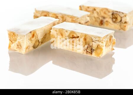 Torrone festivo italiano (o torrone) con nocciole su sfondo bianco. Foto Stock