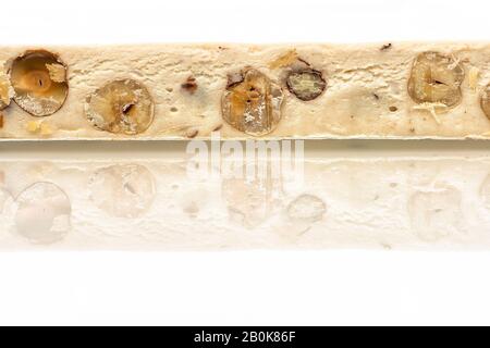 Torrone festivo italiano (o torrone) con nocciole su sfondo bianco. Foto Stock