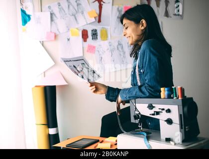 Ritratto di giovane stilista femminile nel suo laboratorio. Giovane ragazza freelancer di successo Foto Stock