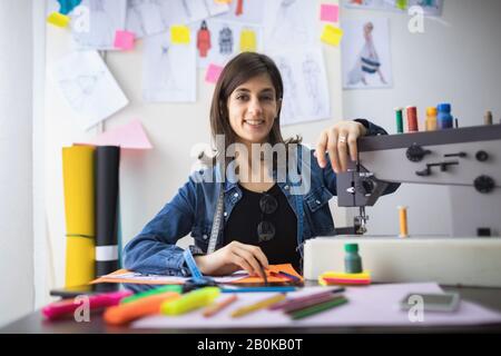 Ritratto di giovane stilista femminile nel suo laboratorio. Giovane ragazza freelancer di successo Foto Stock