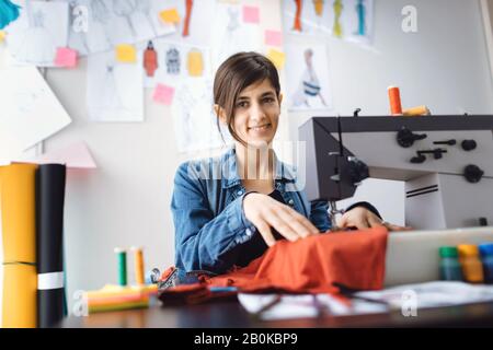 Giovane designer di moda cucito in officina. Lavorazione su misura della macchina da cucire. Concetto di piccola impresa. Foto Stock