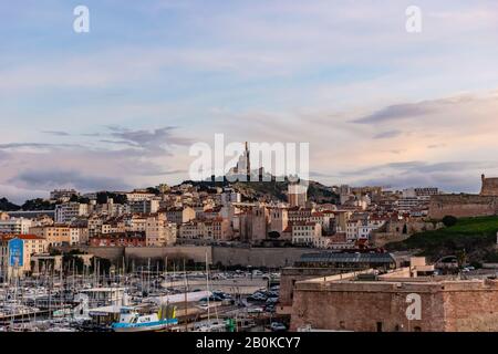 Marsiglia, Francia - 25 gennaio 2020: La vista della Basilica Notre-Dame de la Garde e del vecchio porto al tramonto Foto Stock