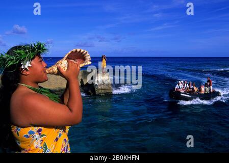 ISOLE COOK, ISOLA DI ATIU, RAGAZZA CHE SOFFIA IN SEASHELL (CORNO), SALUTARE I TURISTI A ZODIAC Foto Stock