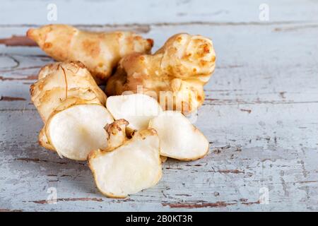 Fresh topinambur sul vecchio tavolo in legno. Foto Stock