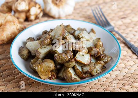 Carciofo di Gerusalemme fritto piccante con aglio Foto Stock