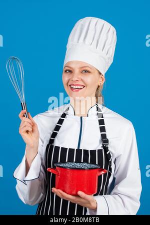 inizio giornata. venite alla mia lezione di cucina. corsi di scuola culinaria. pentole e stoviglie. Cuoca cuoco e masterclass di cibo. Cuoco felice con la casseruola. Donna in grembiule e cappello usa la frusta. Foto Stock