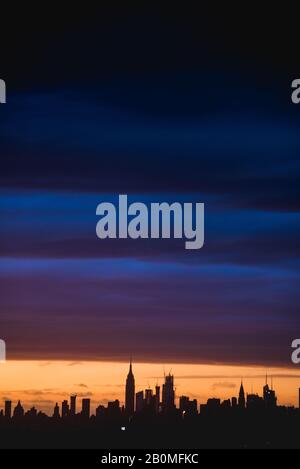 Uno splendido e strano tramonto sullo skyline di Manhattan, come visto da Queens, New York. Foto Stock