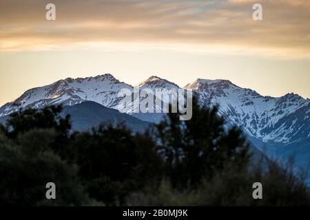 Neve coperta montagna crinale e paesaggio, al tramonto in Nuova Zelanda Foto Stock