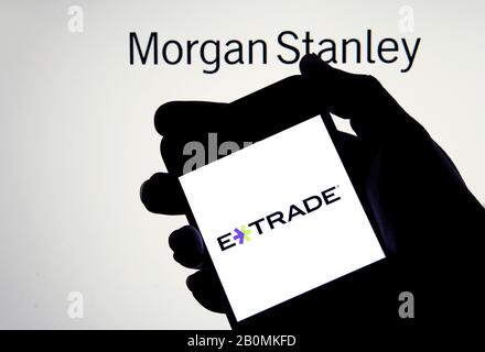 Logo e-trade su uno smartphone in mano con Morgan Stanley sullo sfondo sfocato. Concetto di acquisizione aziendale. Foto reale, non un montaggio. Foto Stock