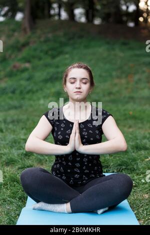 La ragazza rilassata sta facendo yoga nel parco su tappeto Foto Stock