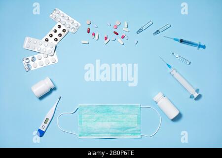 Pillole mediche e capsule in confezioni, una siringa per iniettore su sfondo blu Foto Stock