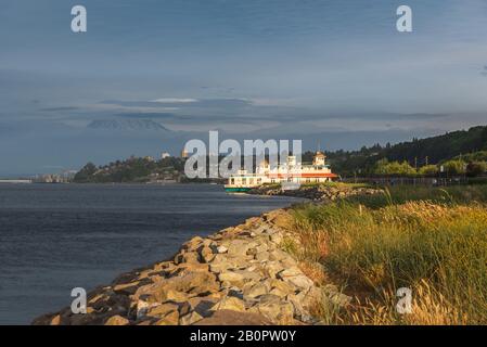 Mt Rainier aleggia sopra il centro cittadino di Tacoma e inizio Bay come si vede dal punto Ruston con la gente a piedi e in bici di equitazione Foto Stock