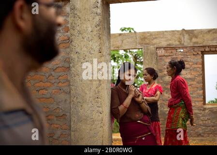 Un uomo non identificato che passa la comunità locale e una nuova casa che aiuta a proteggere gli sfollati, un anno dopo i terremoti del Nepal del 2015. Foto Stock