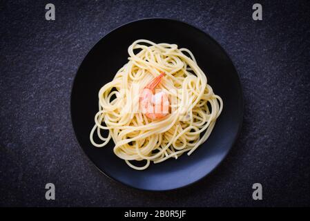 Spaghetti pasta italiana con gamberi prawn servito su piatto sfondo nero / cucina italiana e menu di concetto spaghetti frutti di mare Foto Stock