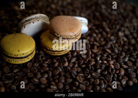 Vista ravvicinata dei macaron di caffè e cioccolato sui chicchi di caffè, macaron dolci francesi Foto Stock