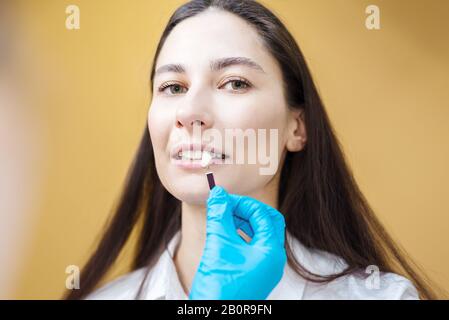 il dentista controlla i denti. Il medico contiene campioni di colore per sbiancamento dei denti. Concetto di igiene orale Foto Stock