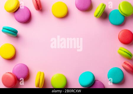 Dessert macaroons su sfondo pastello rosa. Spazio di copia. Vista dall'alto. Foto Stock