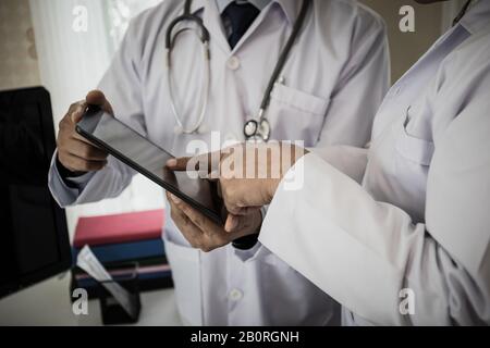 Primo piano di Due medici discutere il lavoro. Mentre si guarda attraverso il tablet insieme in ospedale. Foto Stock